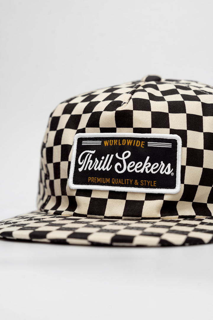 Checkered cap with 'Thrill Seekers' logo on a white background