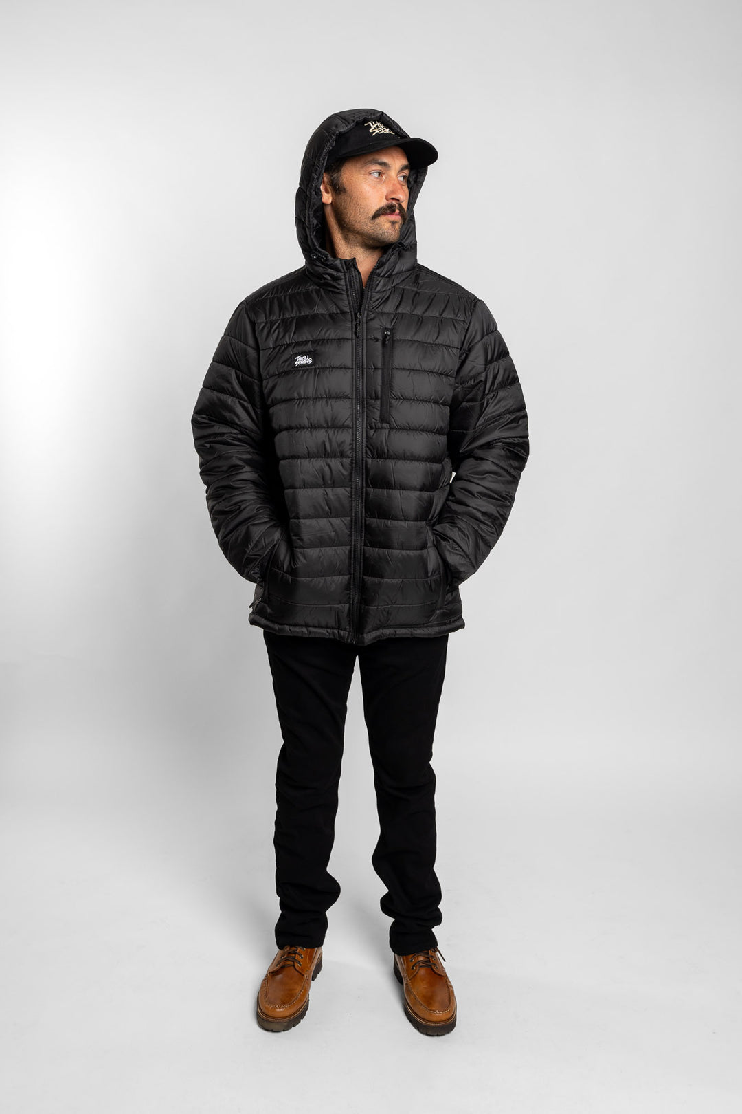 Man wearing a black puffer jacket with a Thrill Seekers logo on a white background