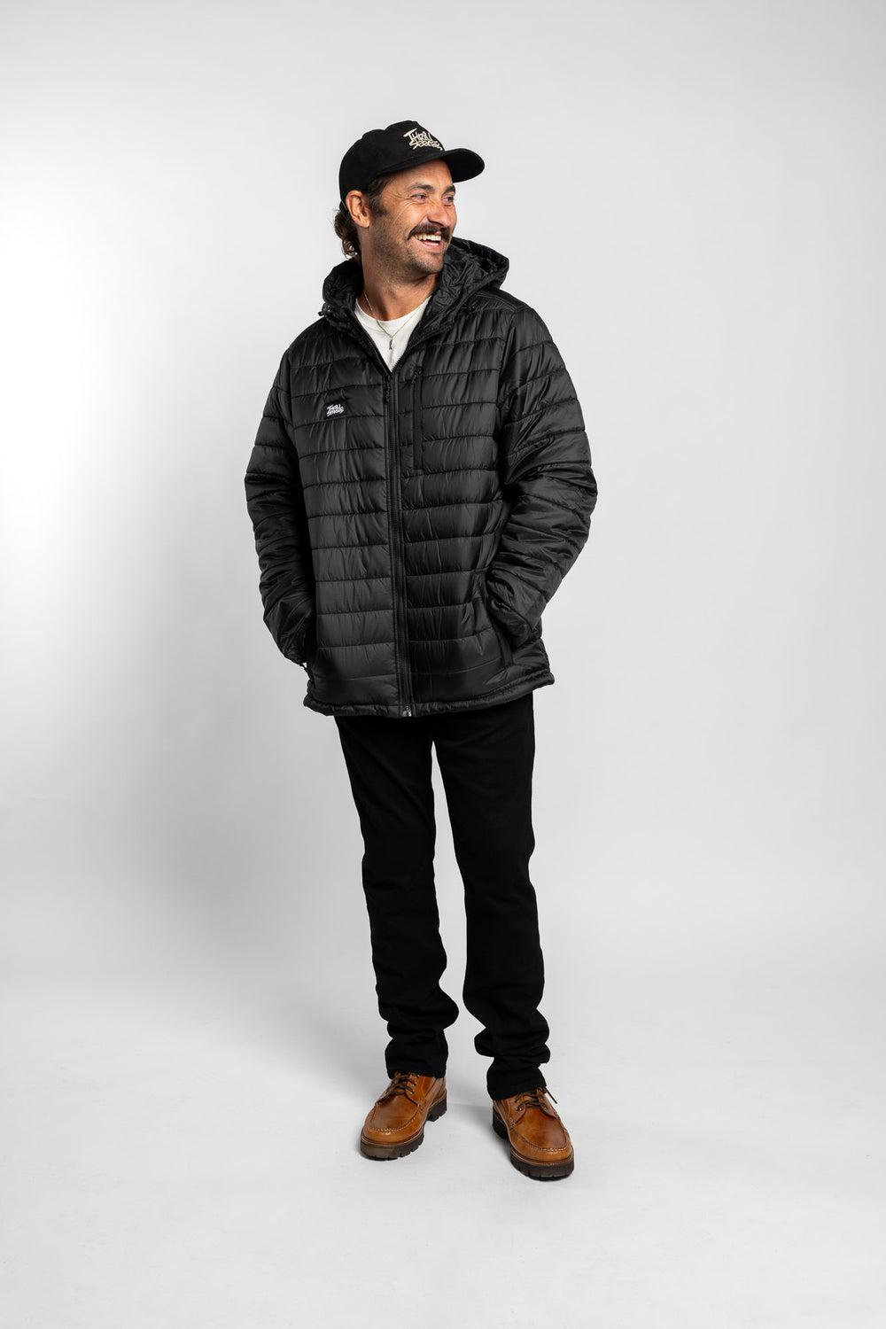 Man wearing a black puffer jacket and cap on a white background