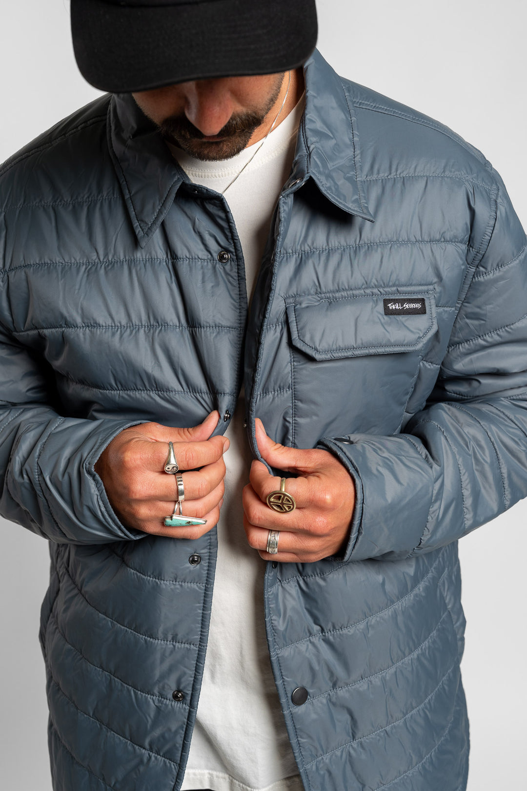 Person wearing a blue quilted jacket with a Thrill Seekers logo on a white background