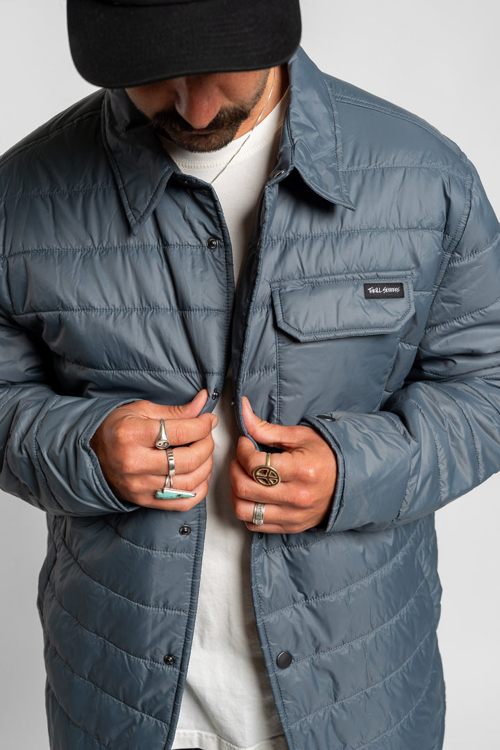 Person wearing a blue quilted jacket with a Thrill Seekers logo on a white background