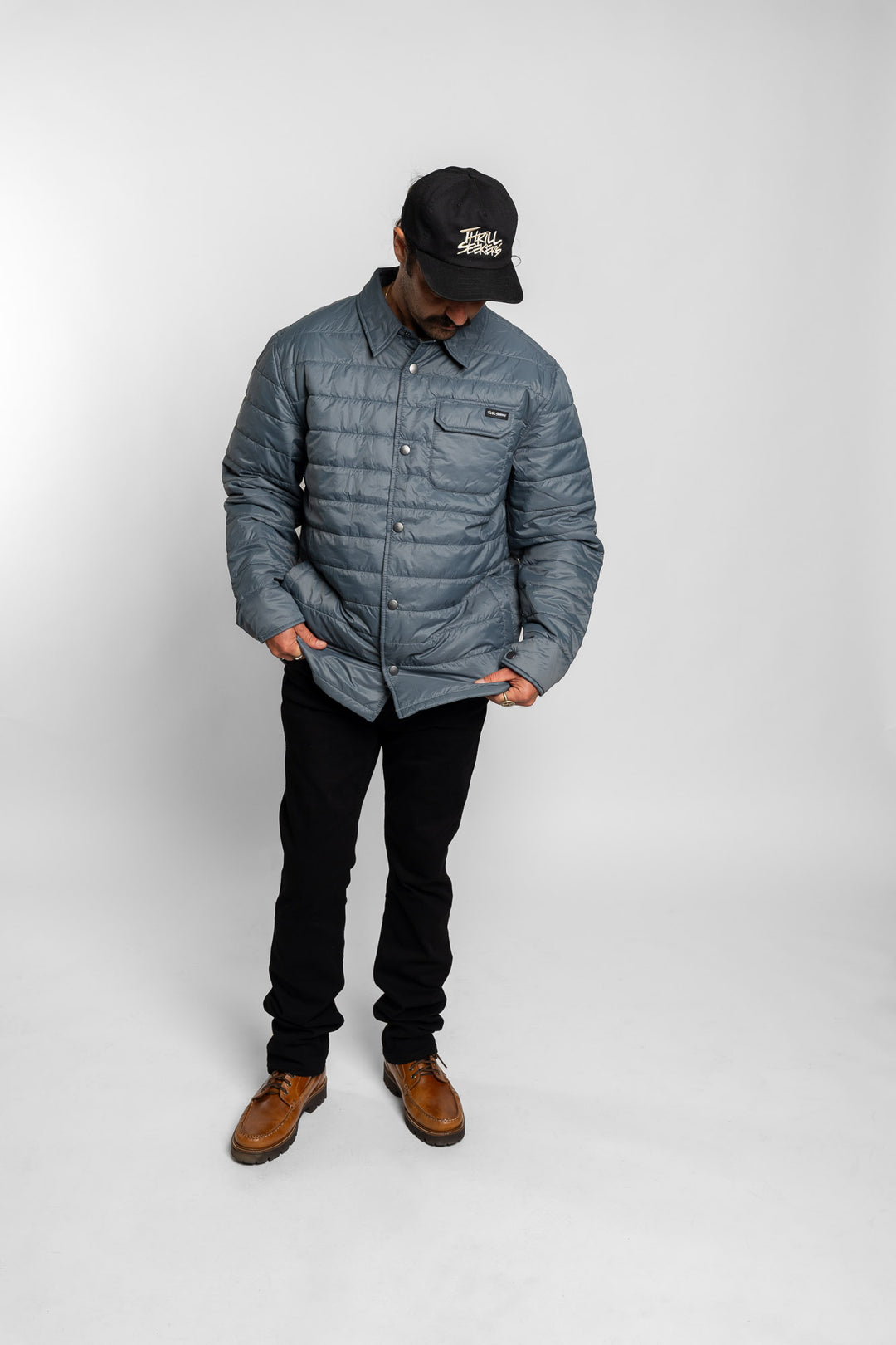 Person wearing a blue quilted jacket, black pants, and brown boots on a white background