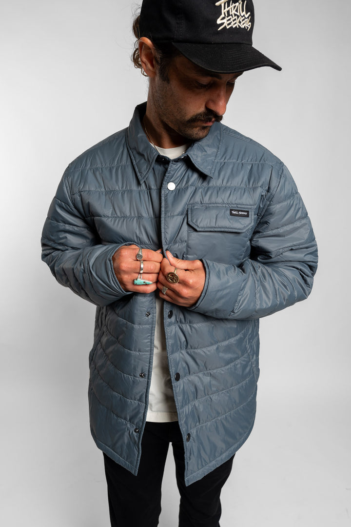 Man wearing a blue quilted jacket and black cap on a white background