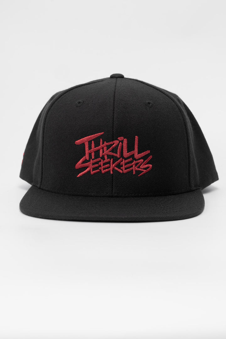 Black snapback hat with 'Thrill Seekers' logo in cardinal red
