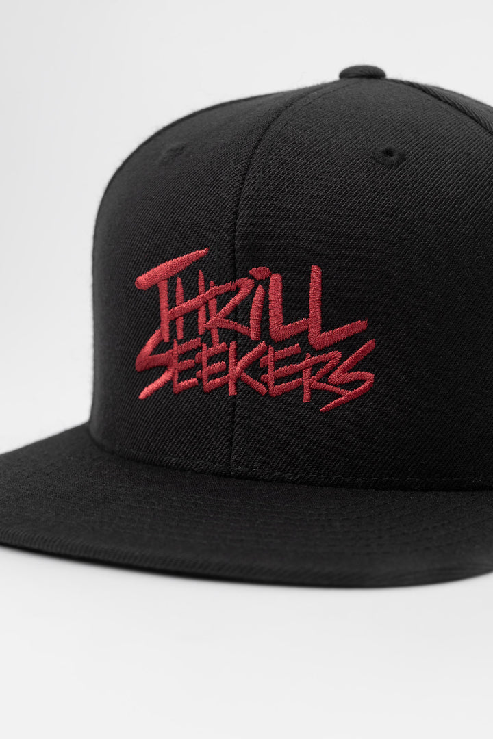 Black snapback hat with 'Thrill Seekers' logo in cardinal red