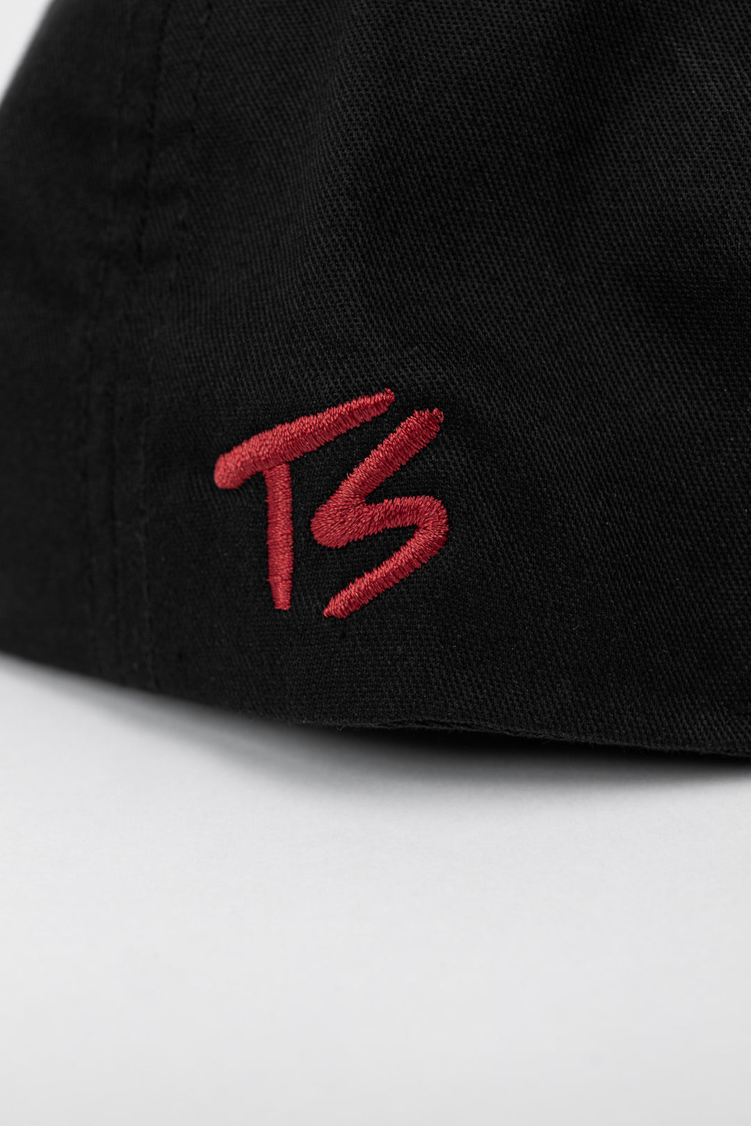 Back of a black cap with cardinel red embroidered logo on a white background