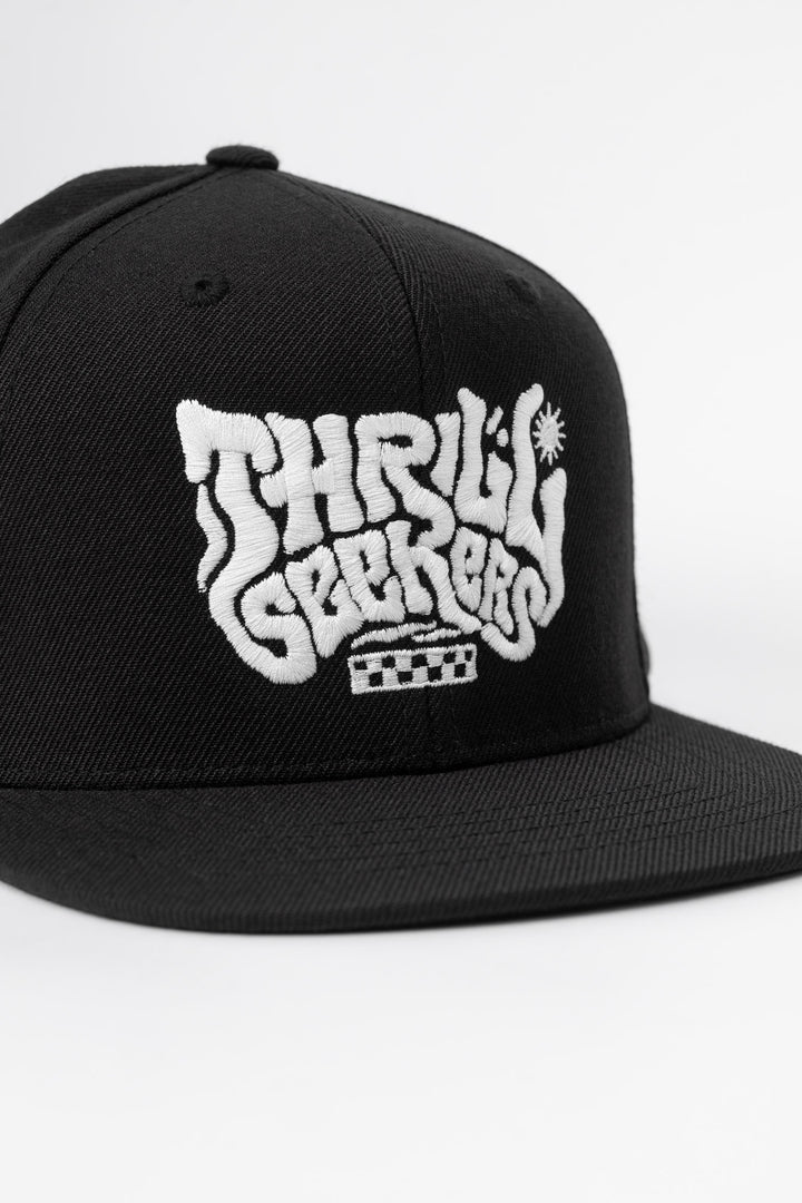 Kids black cap with 'Thrill Seekers' white logo on a white background