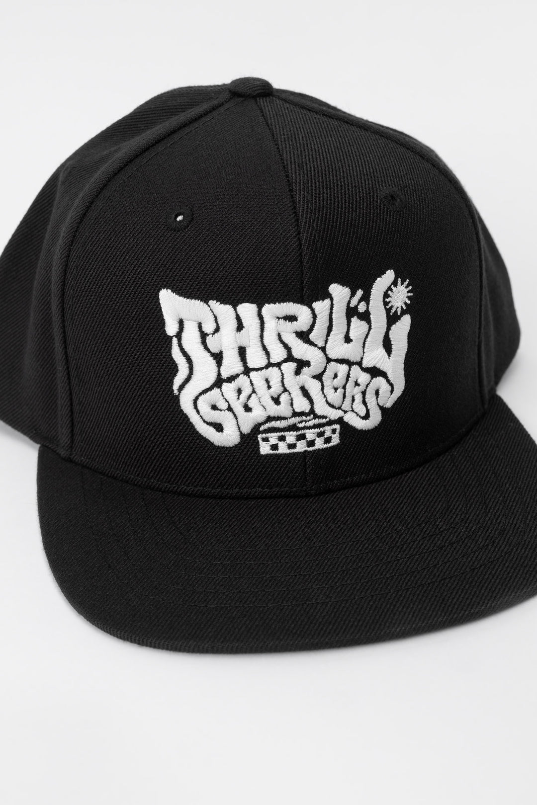Kids black cap with 'Thrill Seekers' white logo on a white background