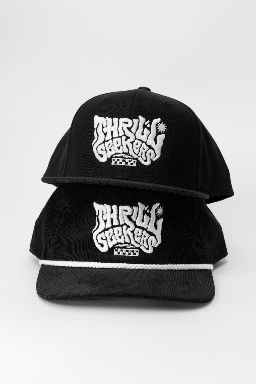 One black adult hat and kids hat, with 'Thrill Seekers' smokin' white logo on a white background