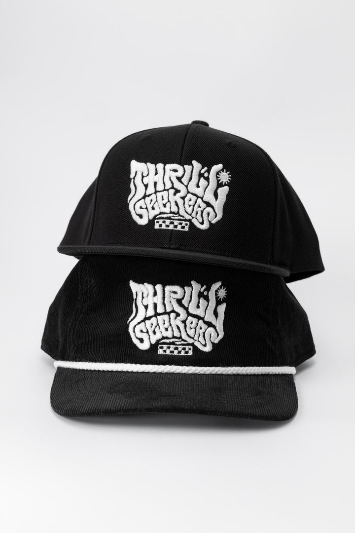 One black adult hat and kids hat, with 'Thrill Seekers' smokin' white logo on a white background