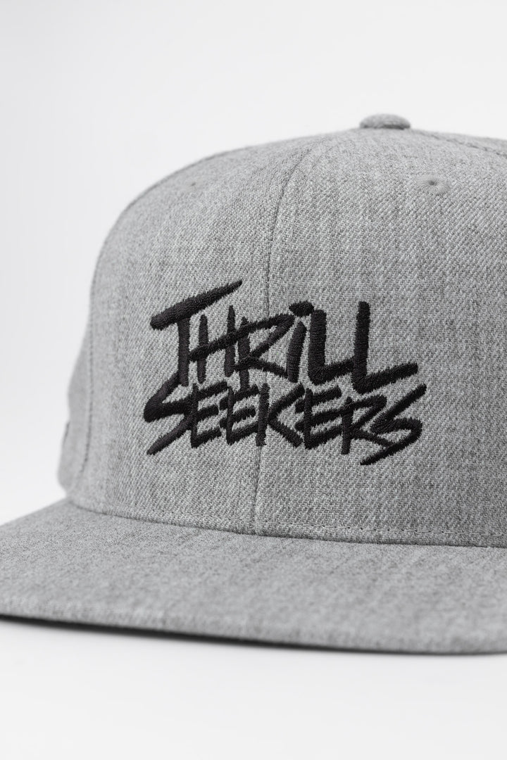 Grey snapback hat with 'Thrill Seekers' logo in black