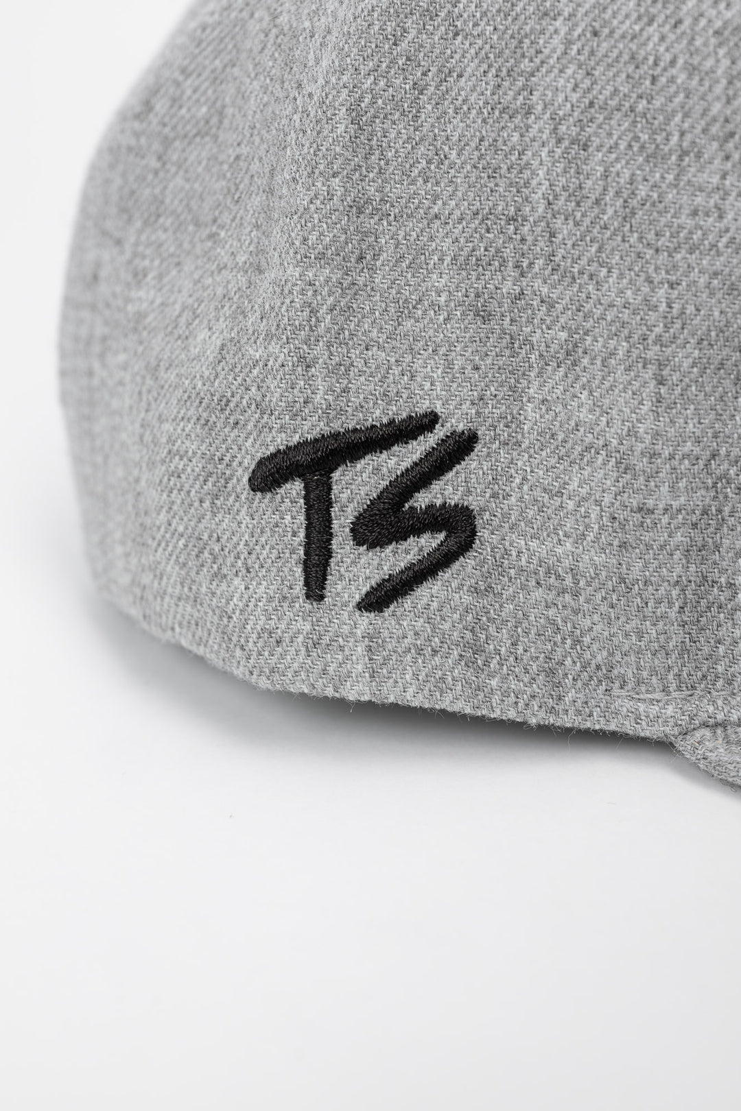 Side profile of grey cap with black 'TS' logo on a white background