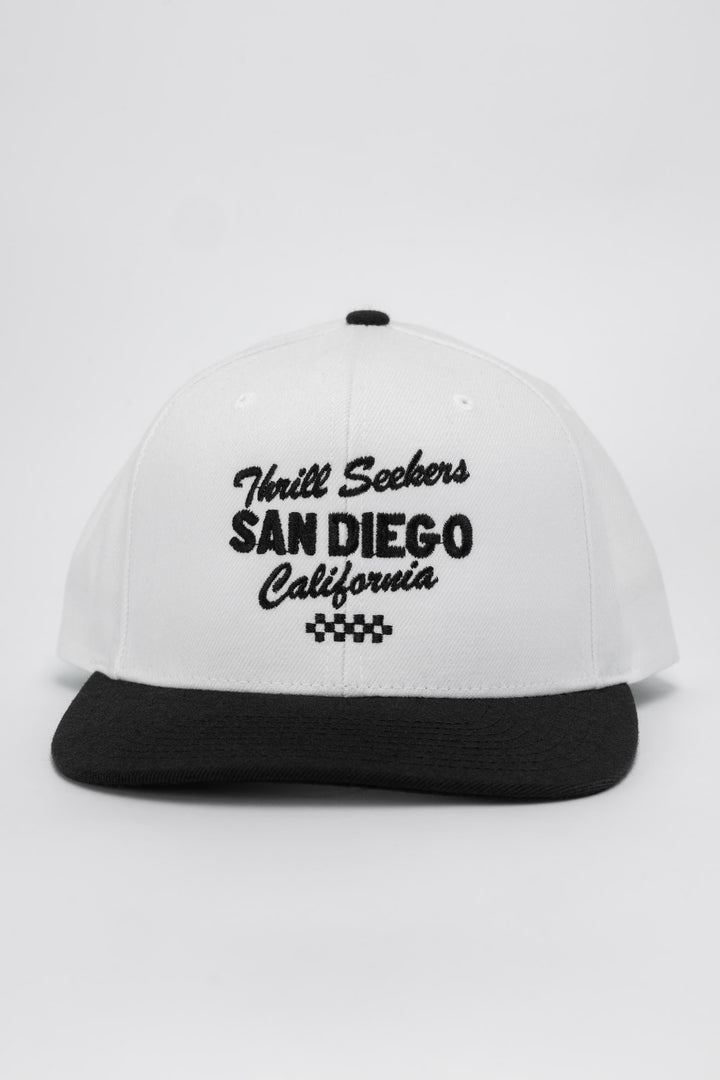 White and black snapback with 'Thrill Seekers' logo in black