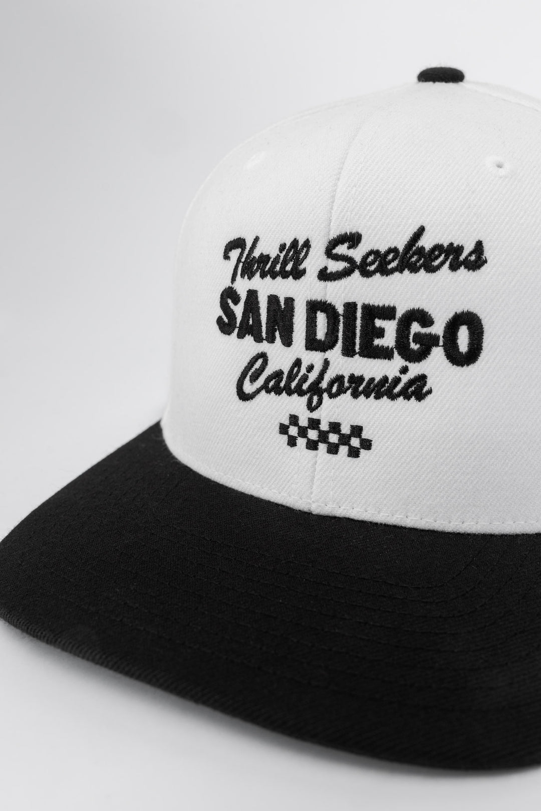 White and black snapback with 'Thrill Seekers' logo in black