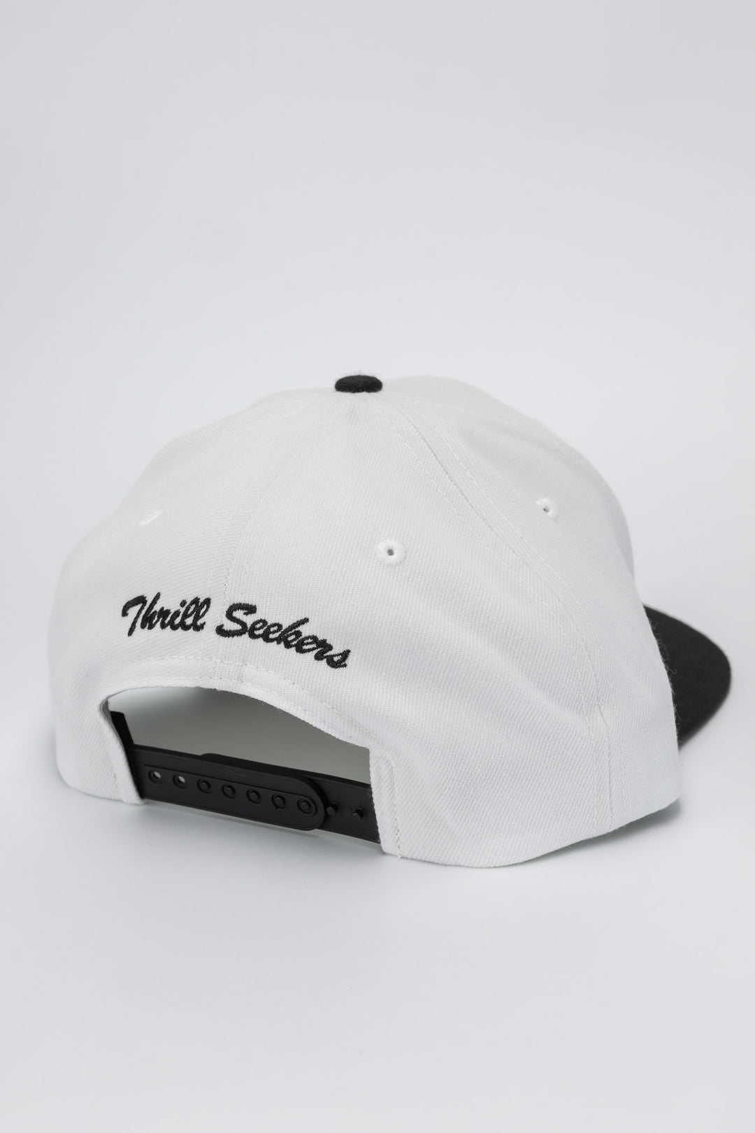 White and black snapback with 'Thrill Seekers' logo in black