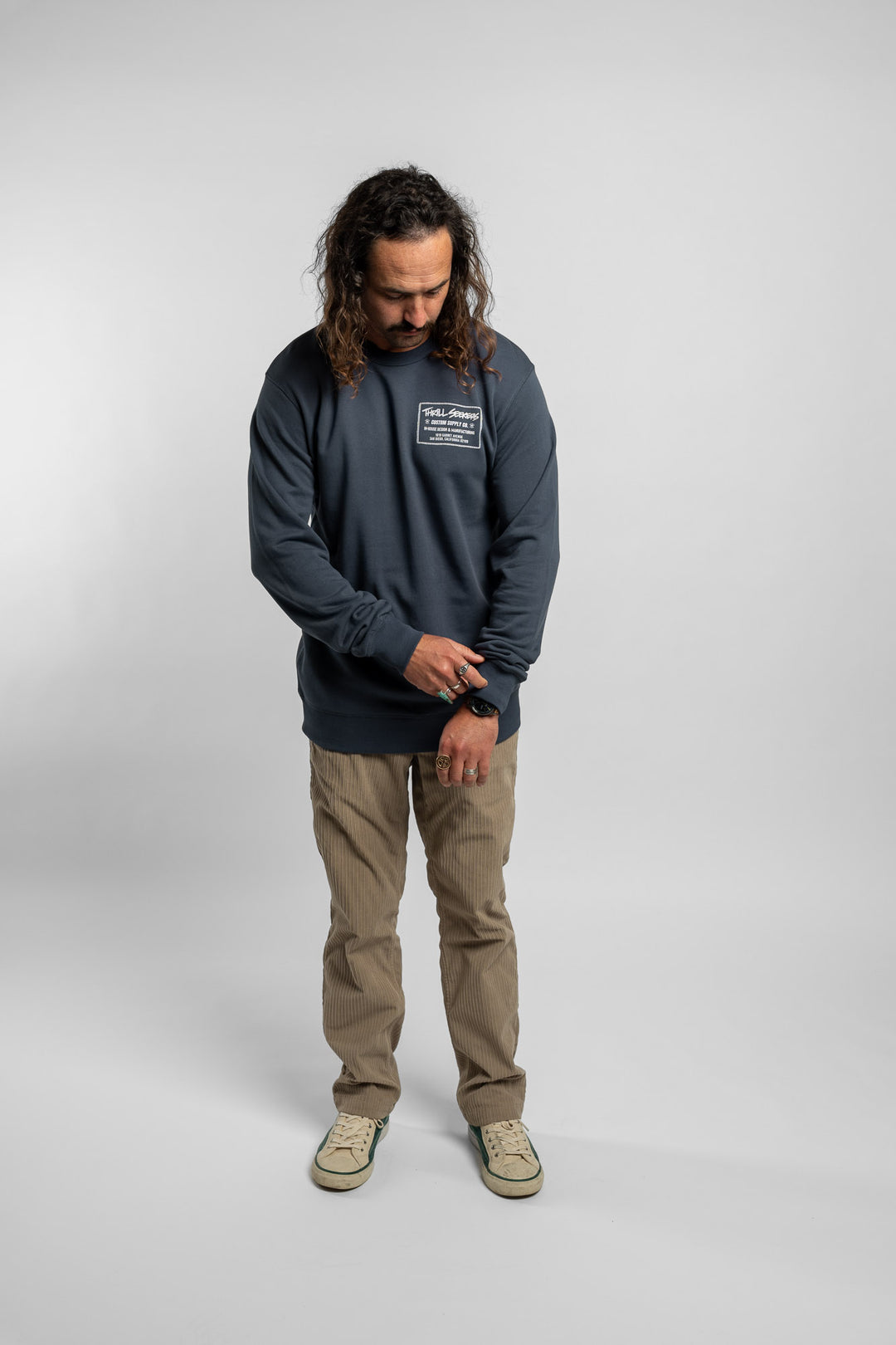 Person wearing a blue crewneck with 'Thrill Seekers' workman logo