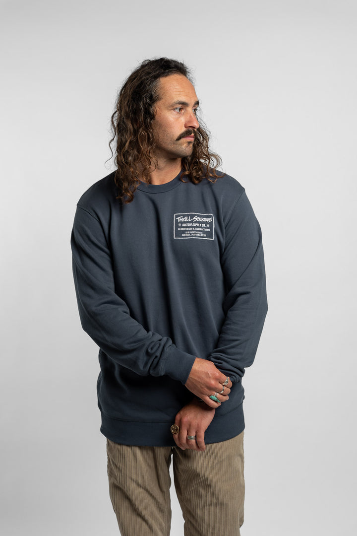 Person wearing a blue crewneck with 'Thrill Seekers' workman logo