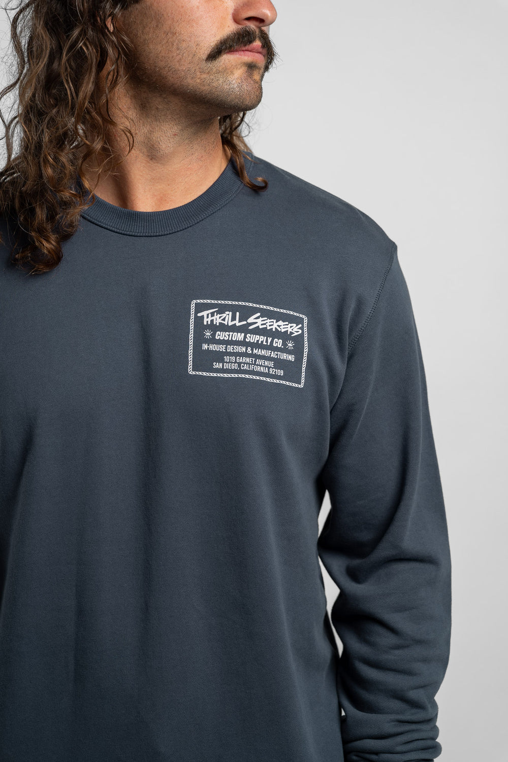Person wearing a blue crewneck with 'Thrill Seekers' workman logo