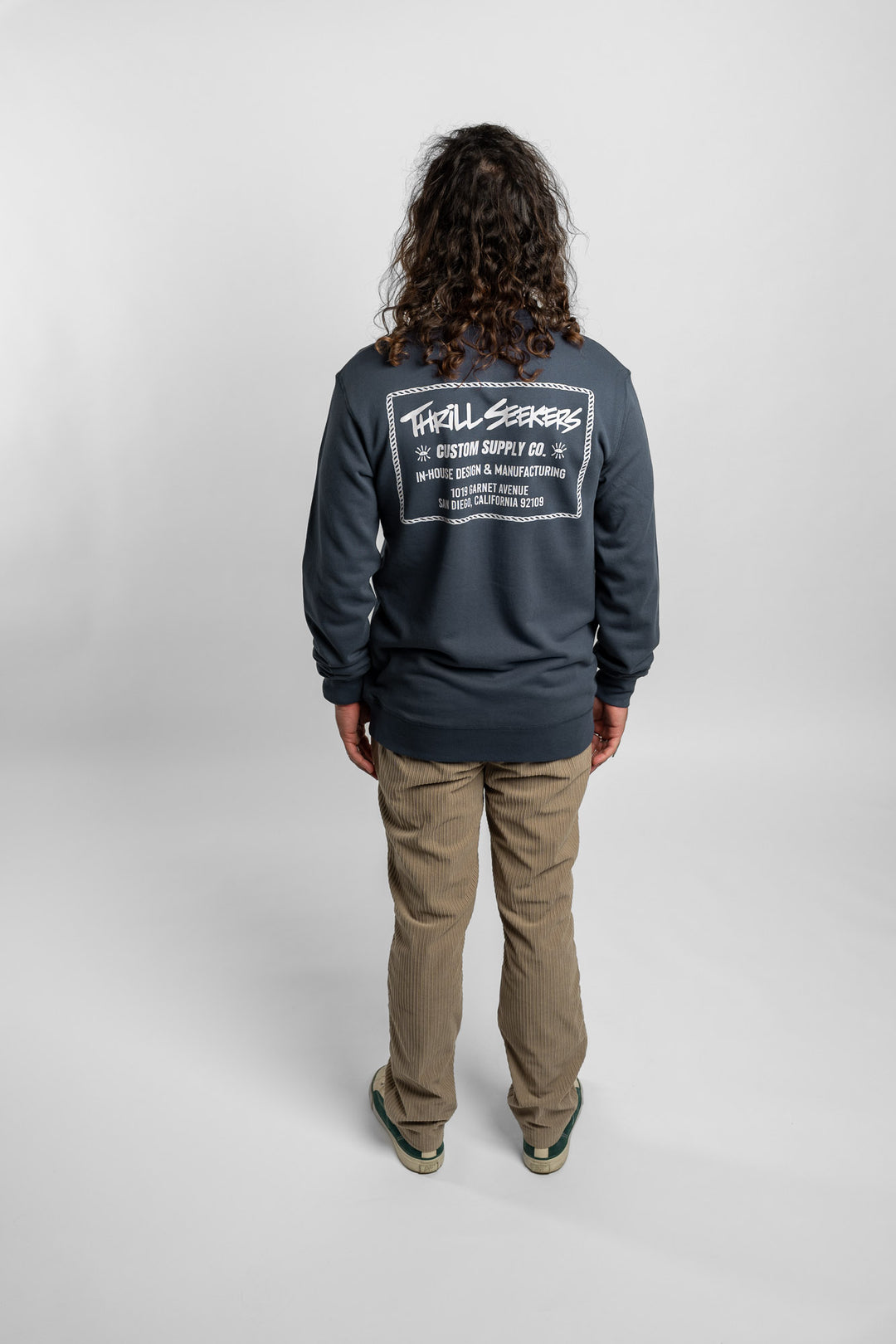 Person wearing a blue crewneck with 'Thrill Seekers' workman logo