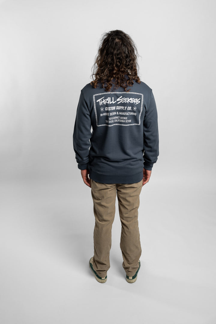 Person wearing a blue crewneck with 'Thrill Seekers' workman logo