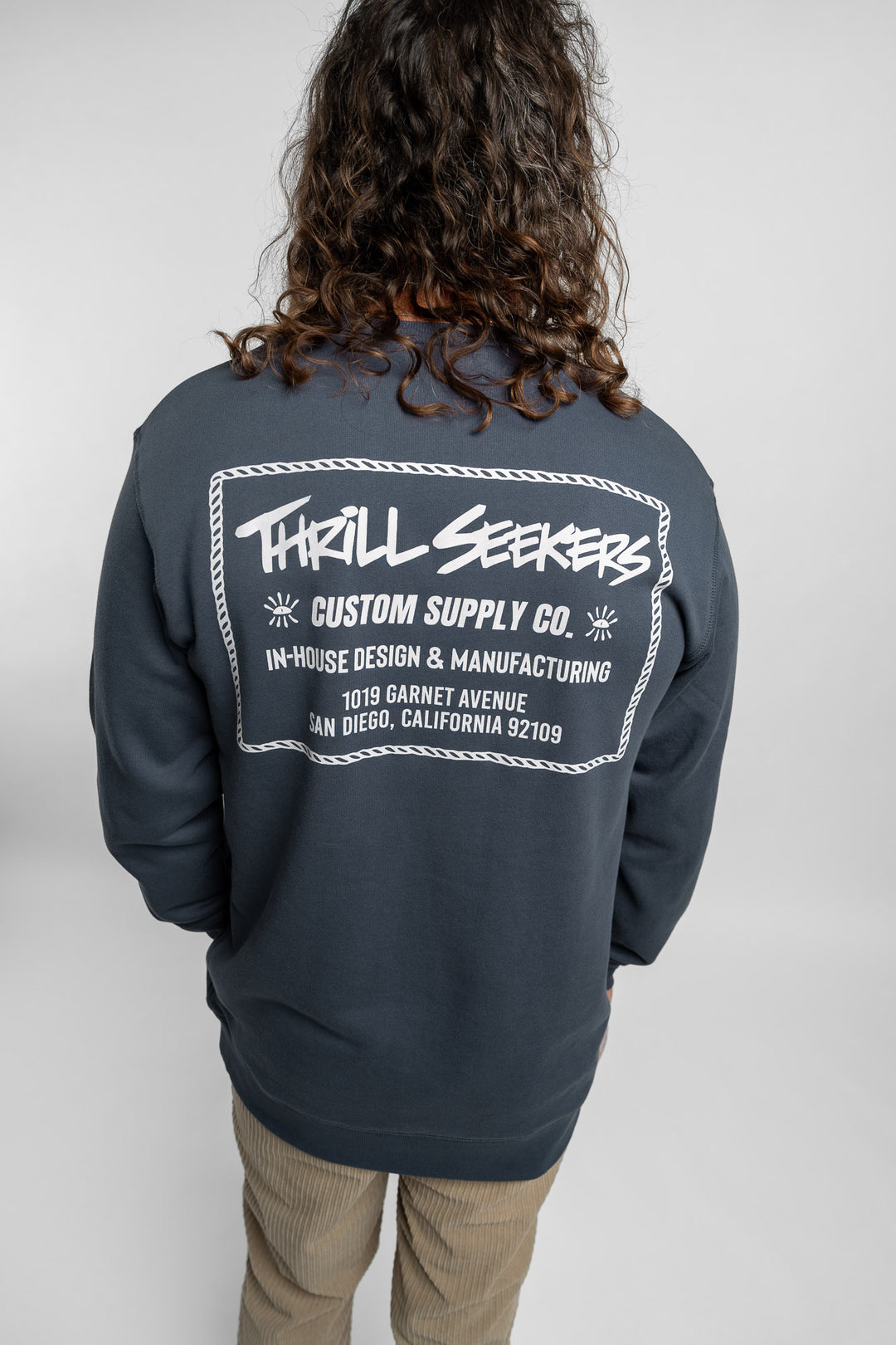 Person wearing a blue crewneck with 'Thrill Seekers' workman logo