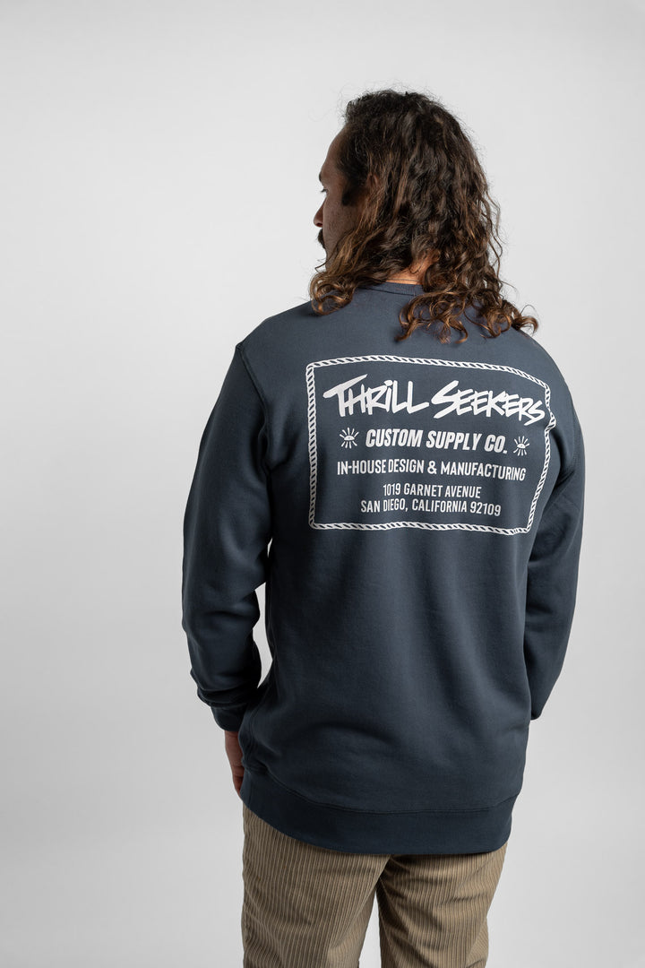 Person wearing a blue crewneck with 'Thrill Seekers' workman logo