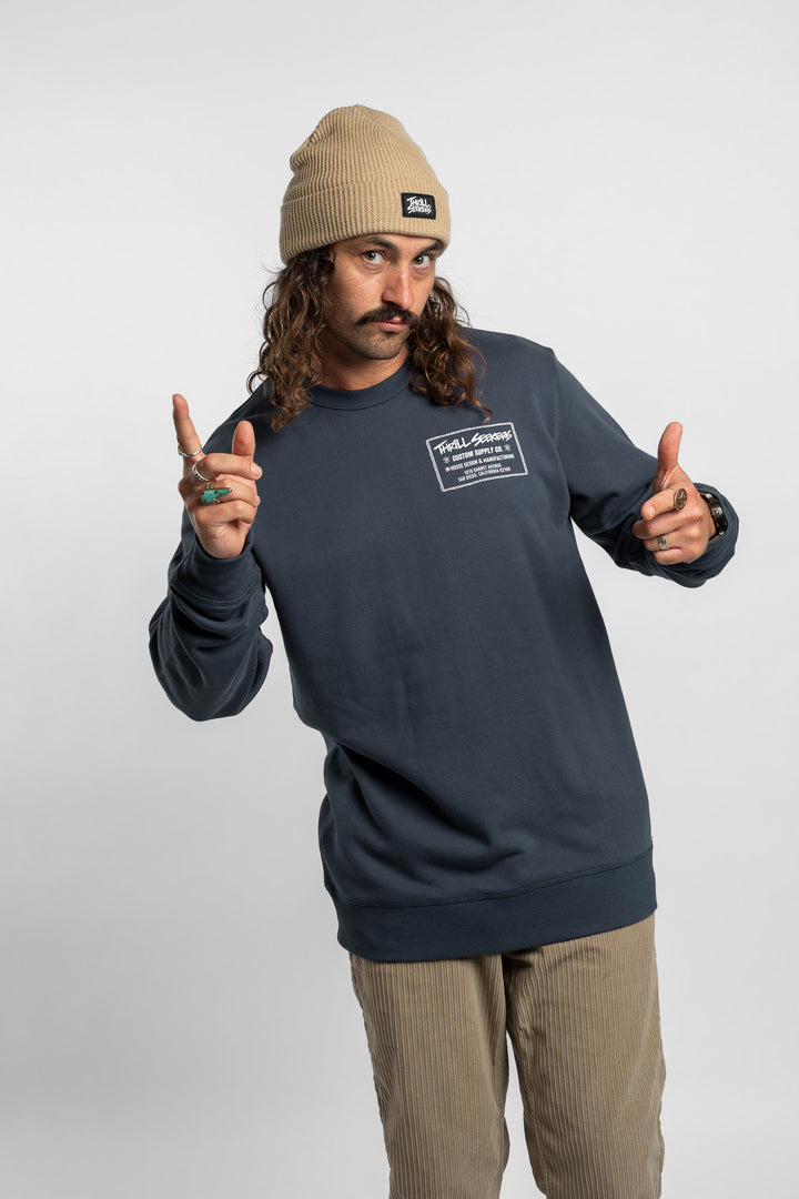 Person wearing a blue crewneck with 'Thrill Seekers' workman logo