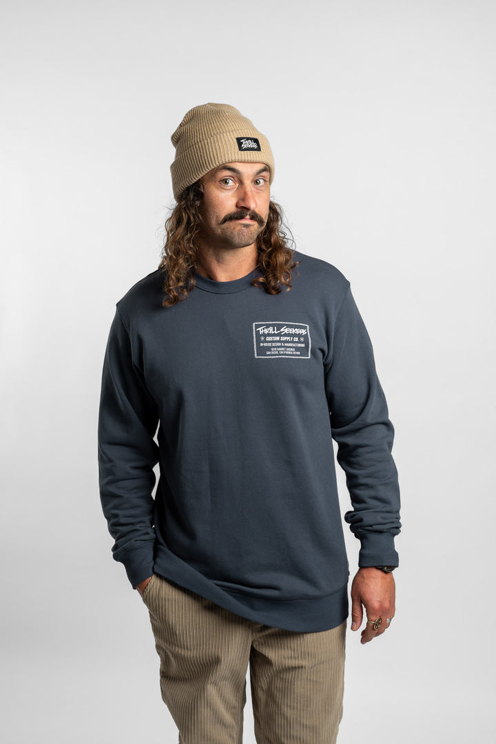 Person wearing a blue crewneck with 'Thrill Seekers' workman logo