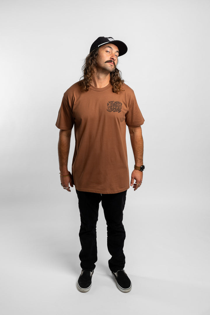 Person wearing cocoa tee with 'Thrill Seekers' scribe logo
