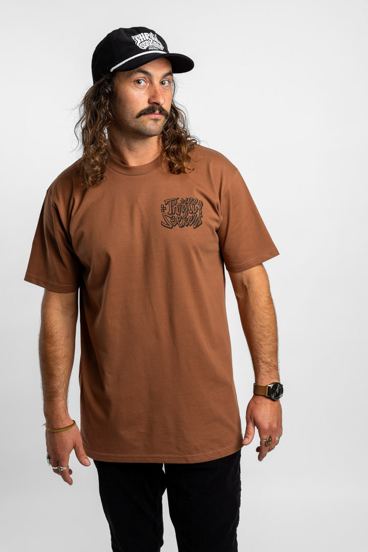 Person wearing cocoa tee with 'Thrill Seekers' scribe logo
