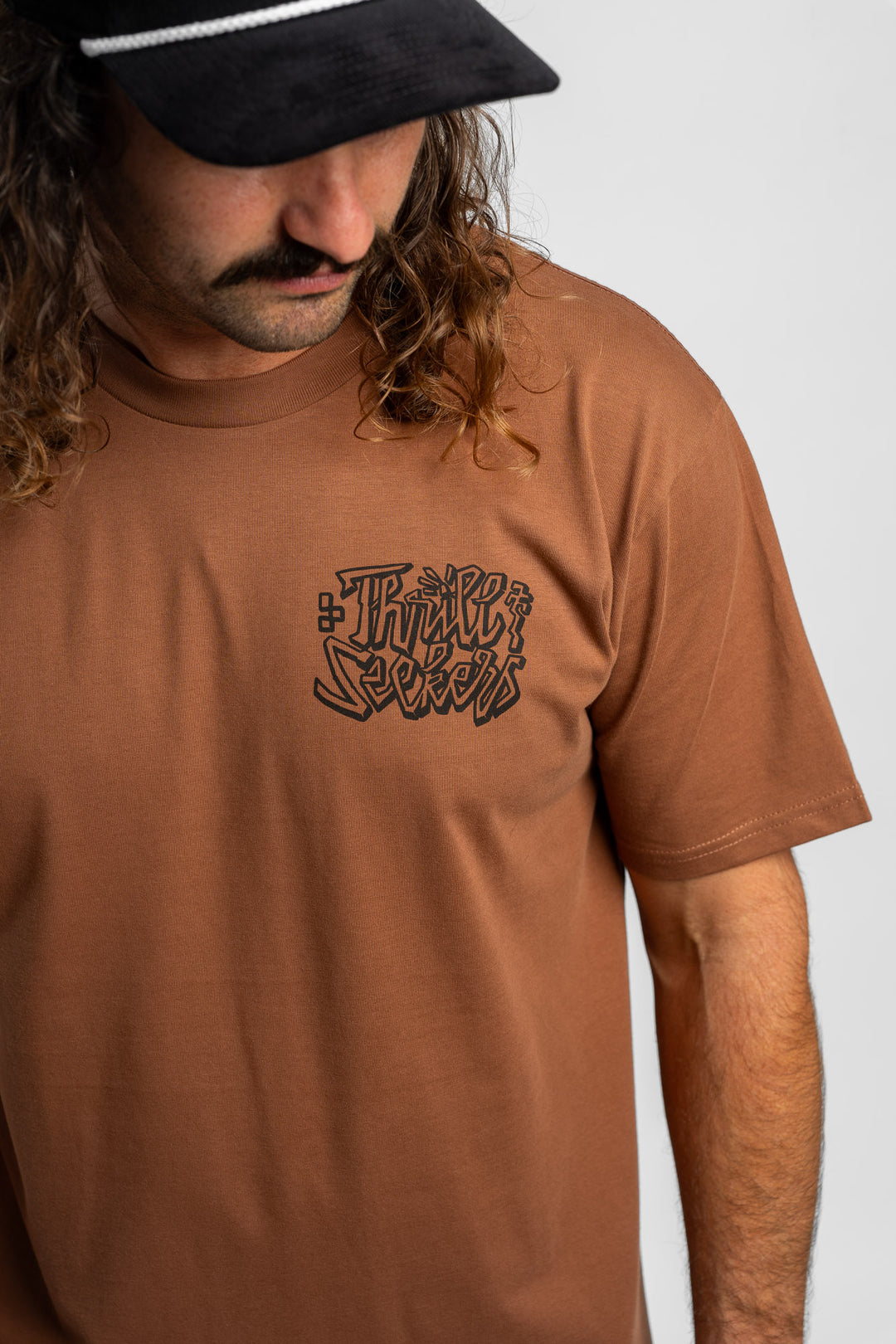 Person wearing cocoa tee with 'Thrill Seekers' scribe logo