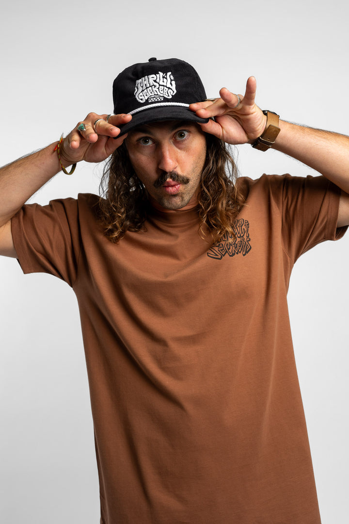 Person wearing a black corduroy cap with 'Thrill Seekers' logo on a white background