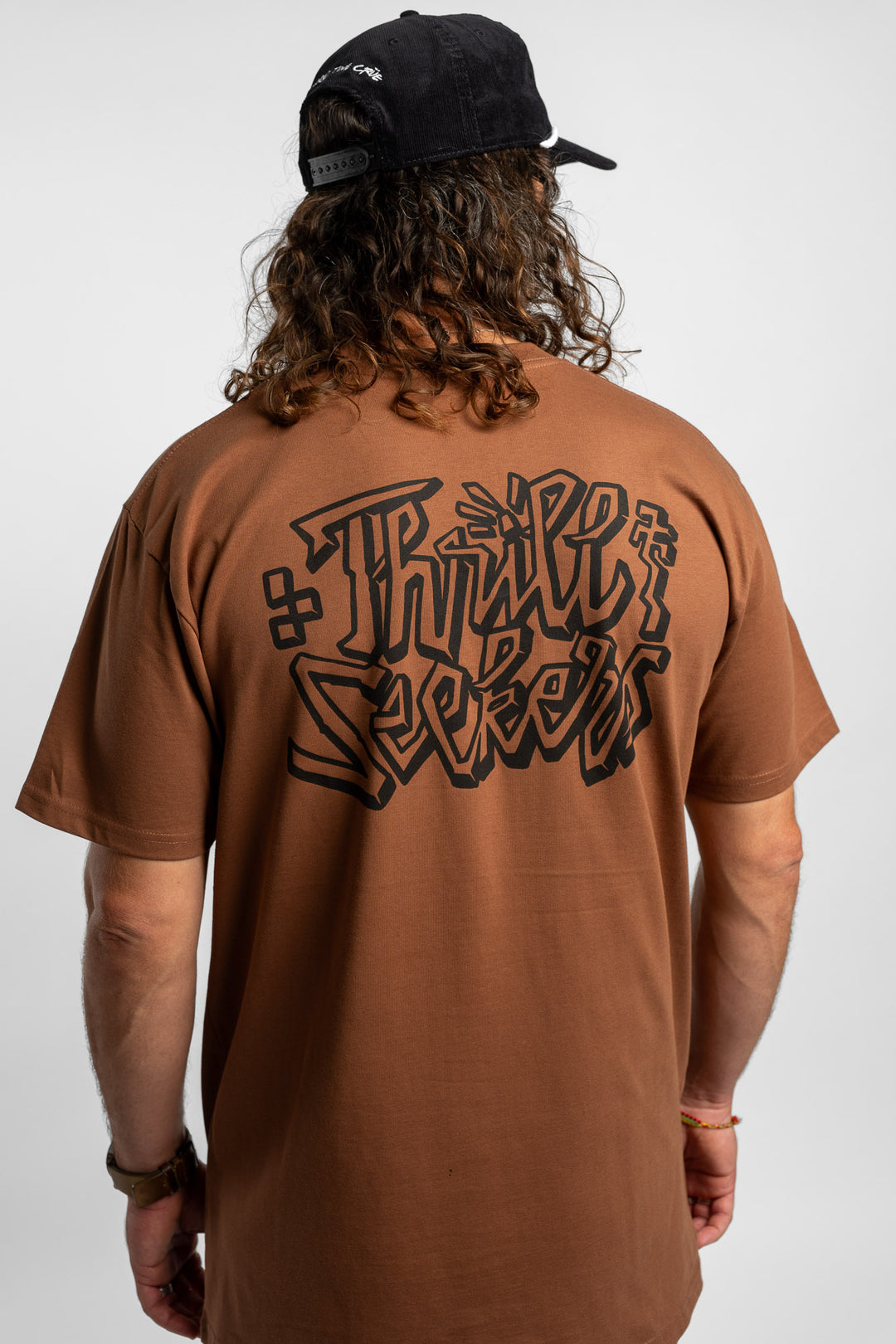 Person wearing cocoa tee with 'Thrill Seekers' scribe logo