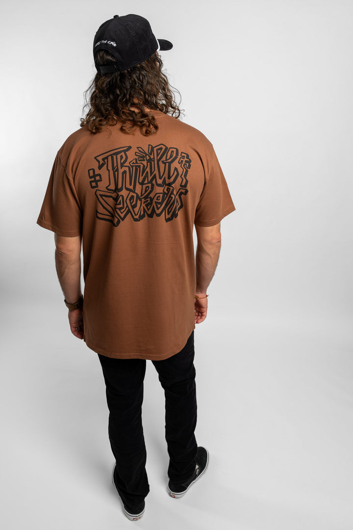 Person wearing cocoa tee with 'Thrill Seekers' scribe logo