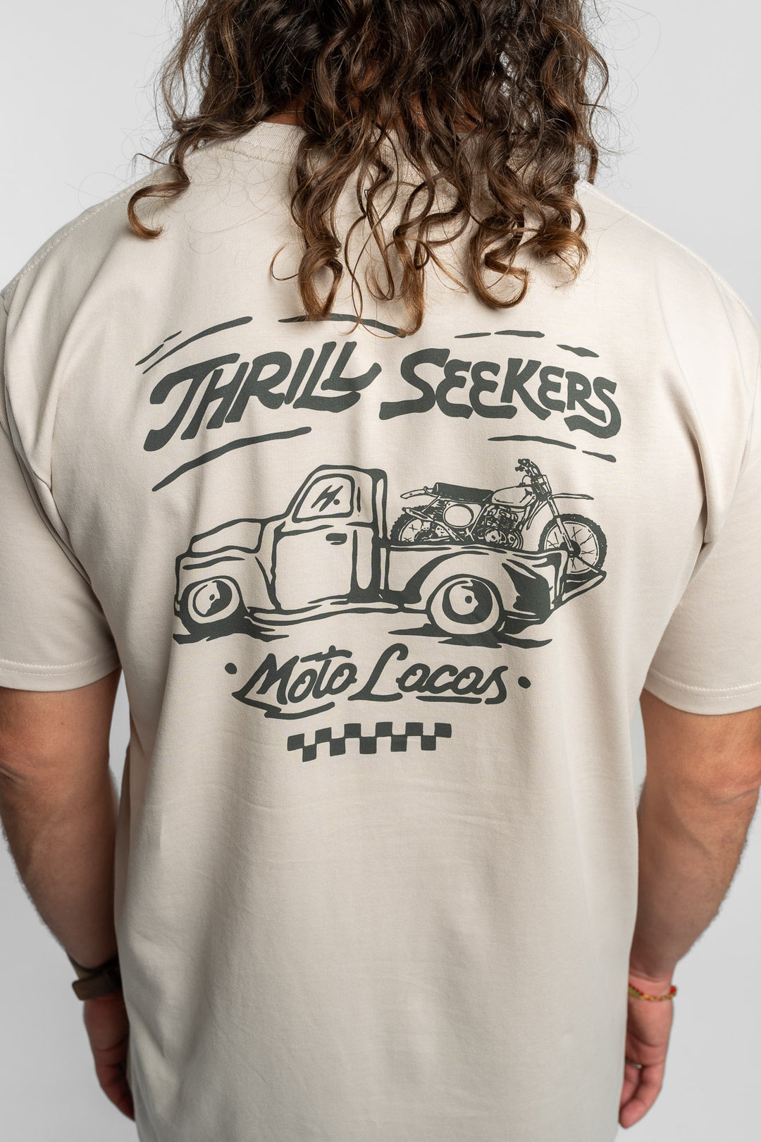 Person wearing bone tee with 'Thrill Seekers' moto locos logo in green