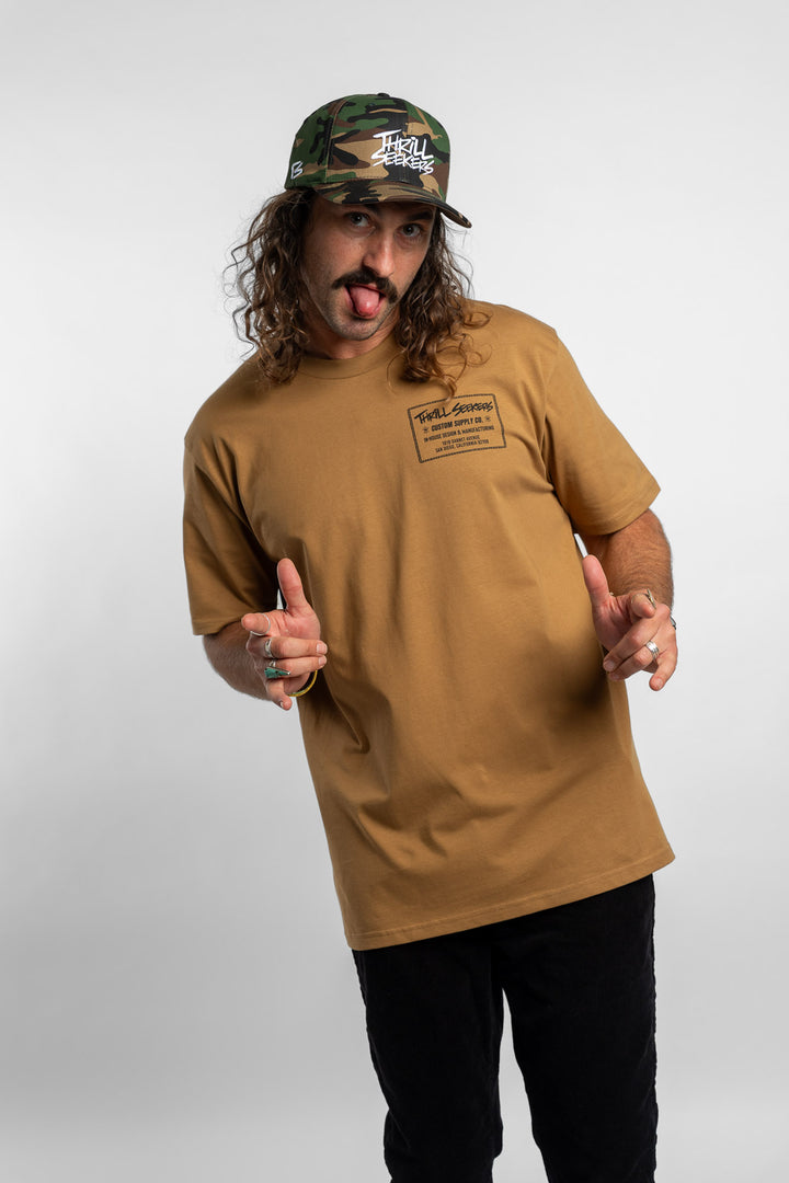 Person wearing a camel tee with a 'Thrill Seekers' workman logo