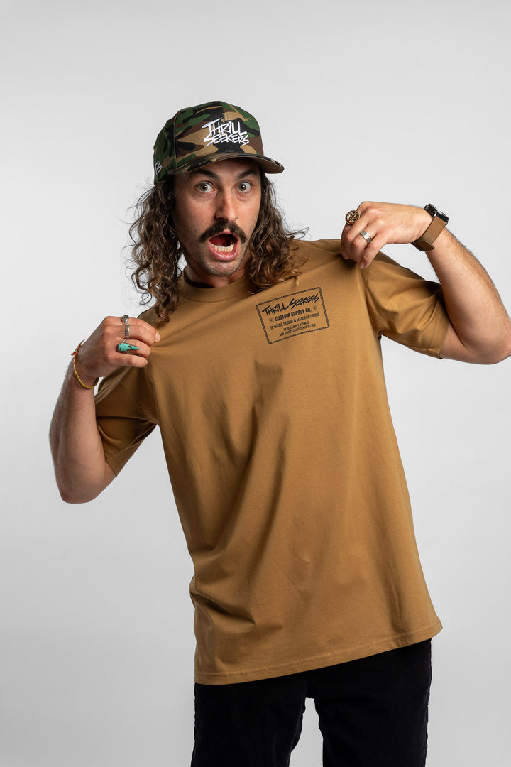 Person wearing a camel tee with a 'Thrill Seekers' workman logo