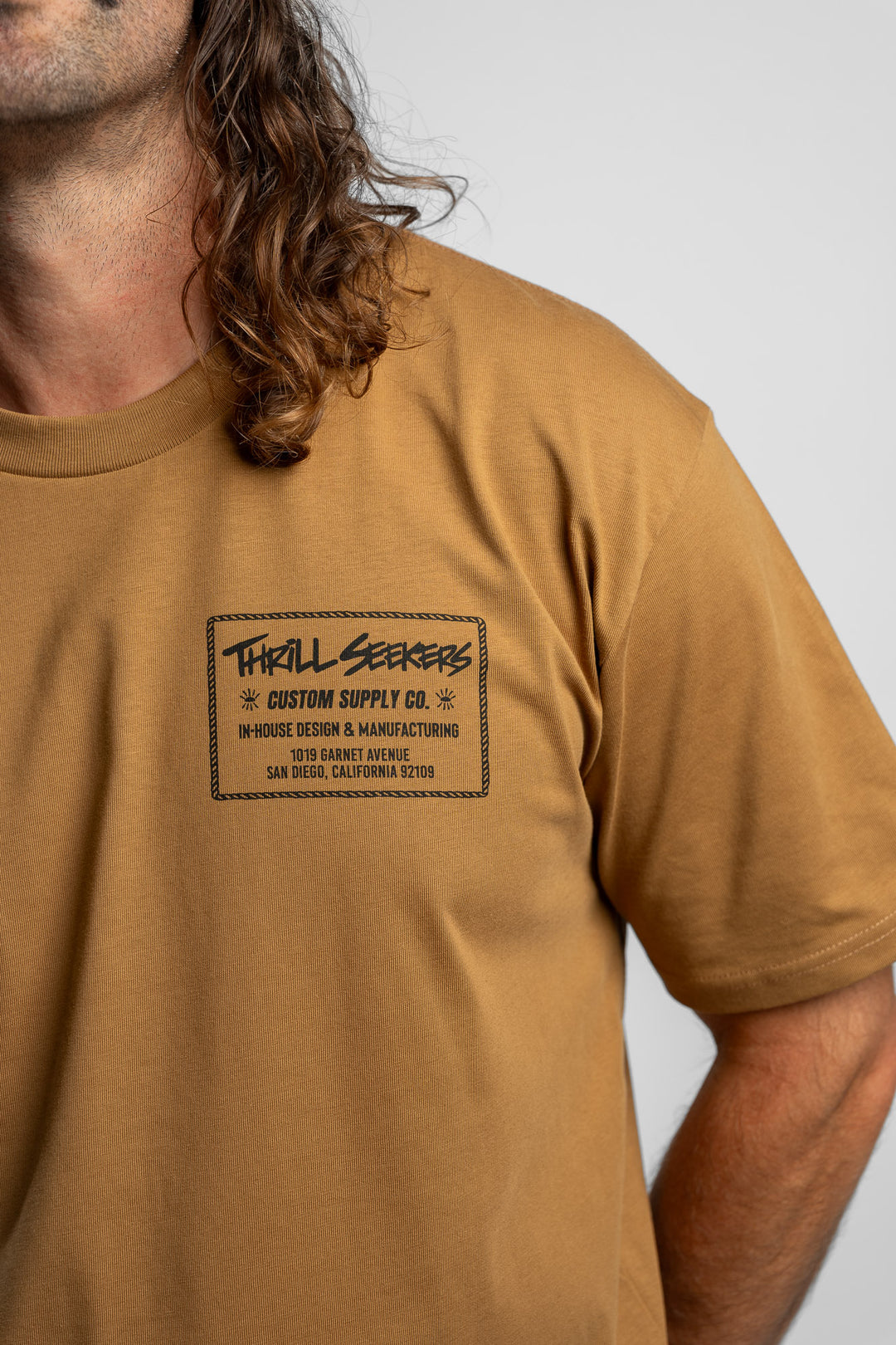Person wearing a camel tee with a 'Thrill Seekers' workman logo