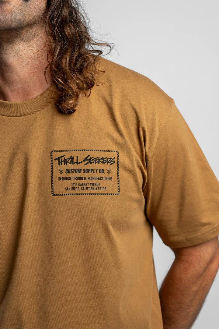 Person wearing a camel tee with a 'Thrill Seekers' workman logo