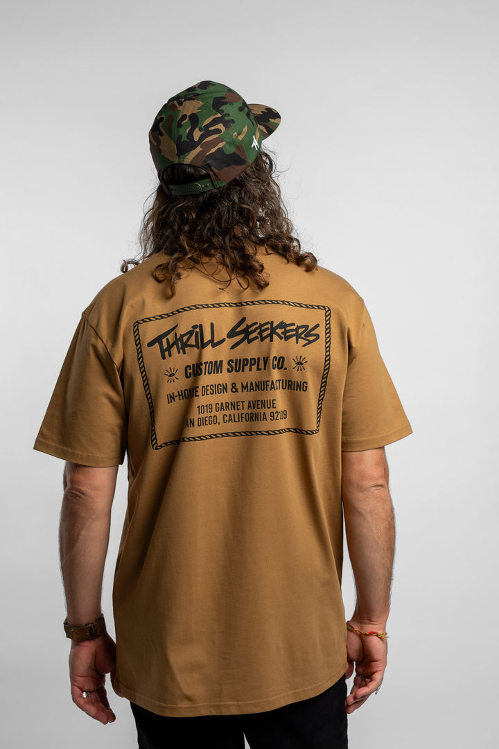 Person wearing a camel tee with a 'Thrill Seekers' workman logo