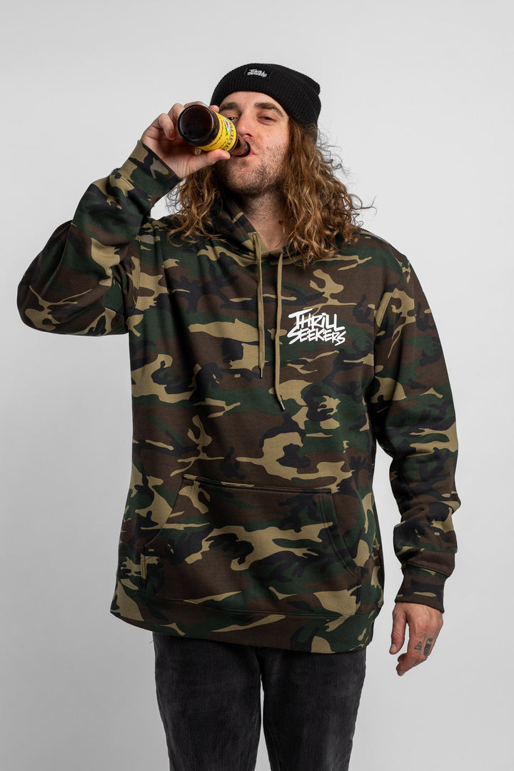 Person wearing camo hoodie with 'Thrill Seekers' logo in white