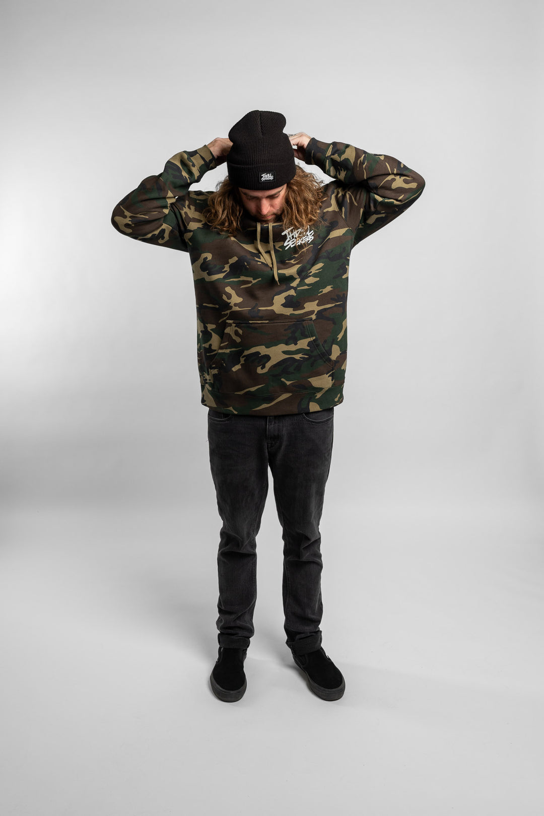 Person wearing camo hoodie with 'Thrill Seekers' logo in white