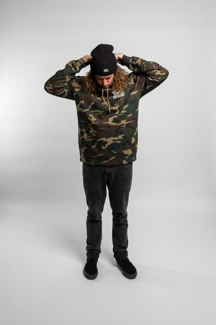 Person wearing camo hoodie with 'Thrill Seekers' logo in white