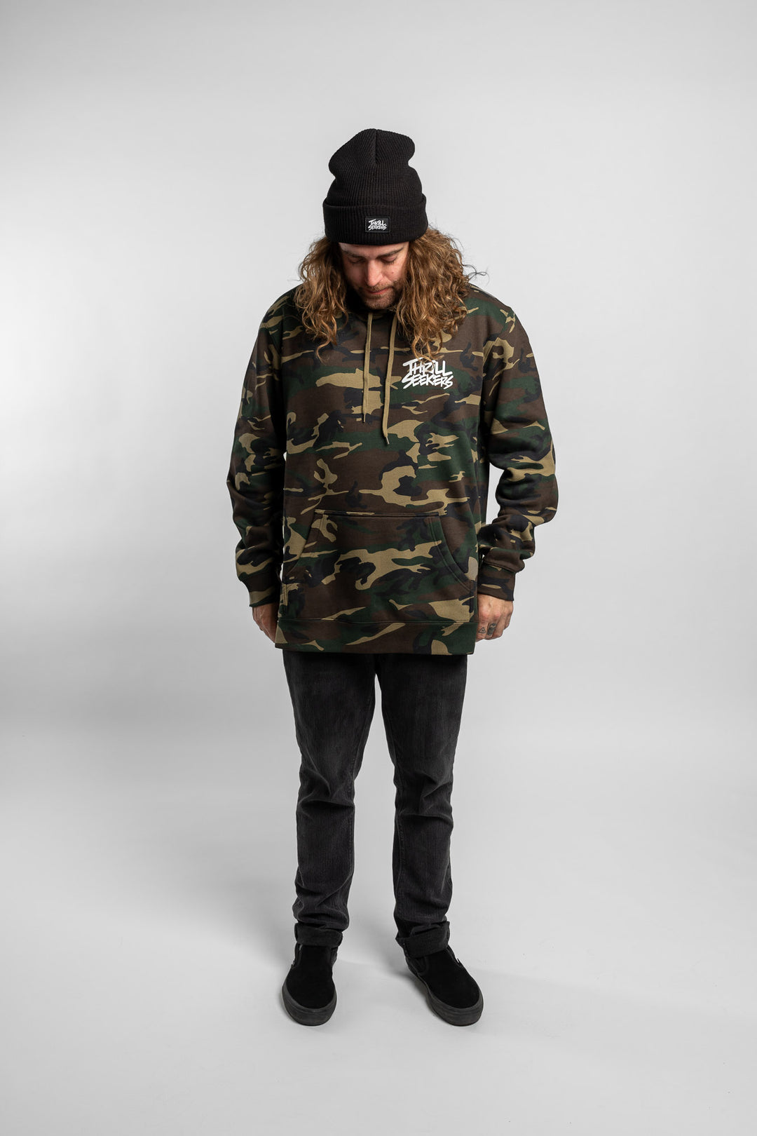 Person wearing camo hoodie with 'Thrill Seekers' logo in white