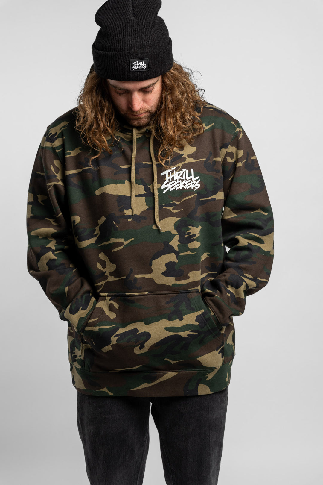 Person wearing camo hoodie with 'Thrill Seekers' logo in white