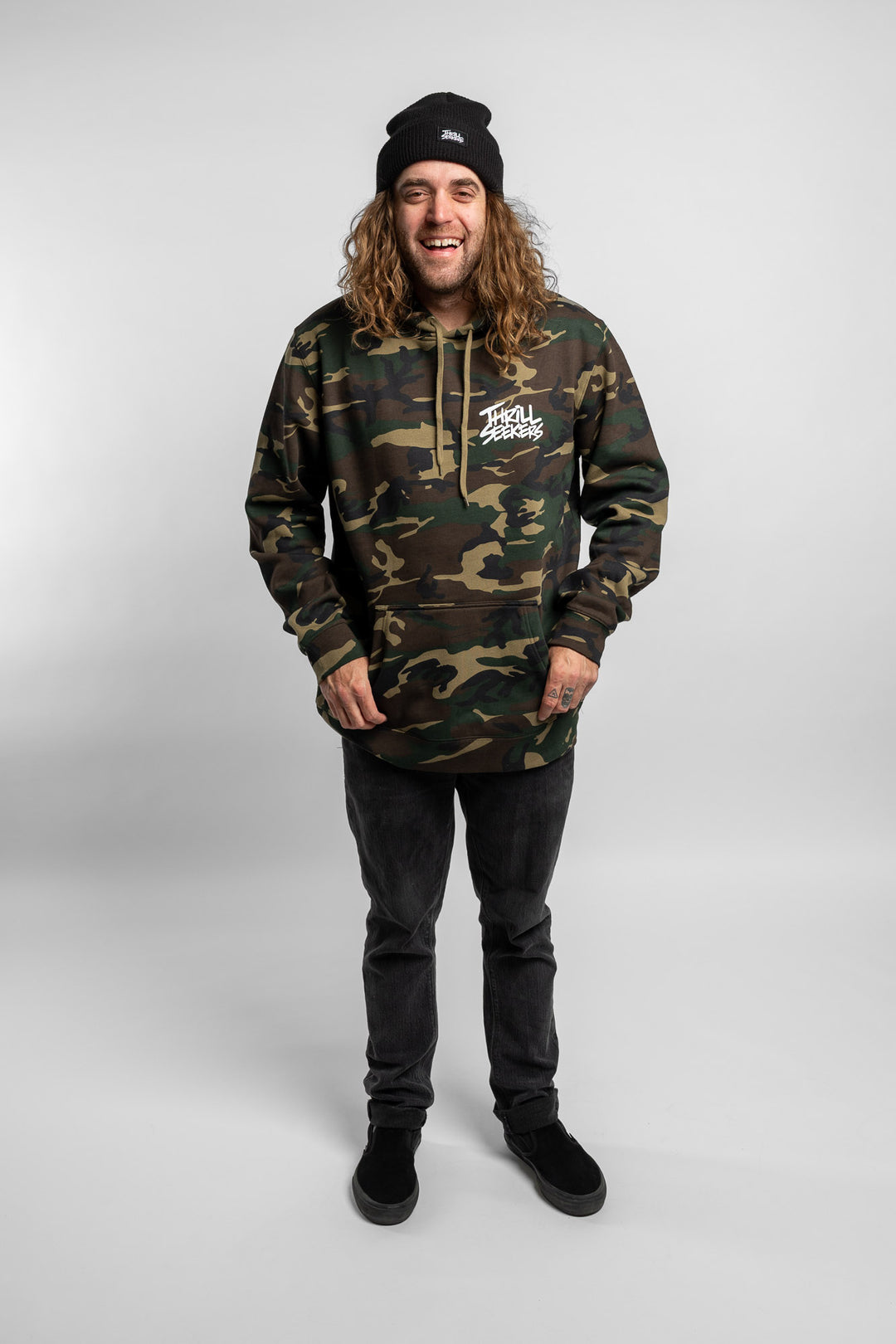Person wearing camo hoodie with 'Thrill Seekers' logo in white