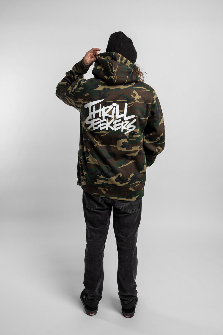 Person wearing camo hoodie with 'Thrill Seekers' logo in white