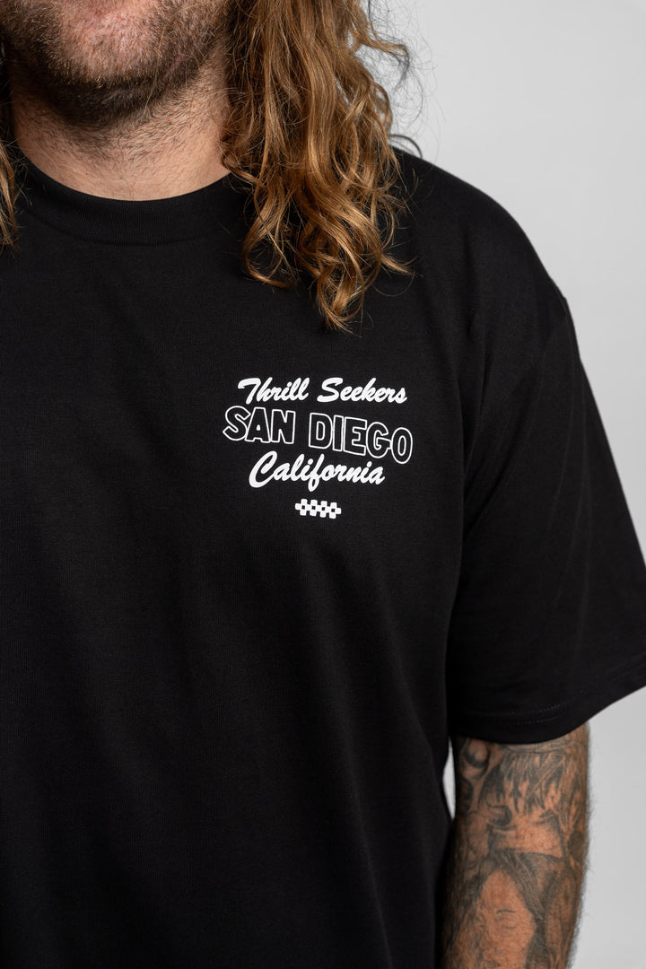 Person wearing black tee with 'Thrill Seekers' shop logo