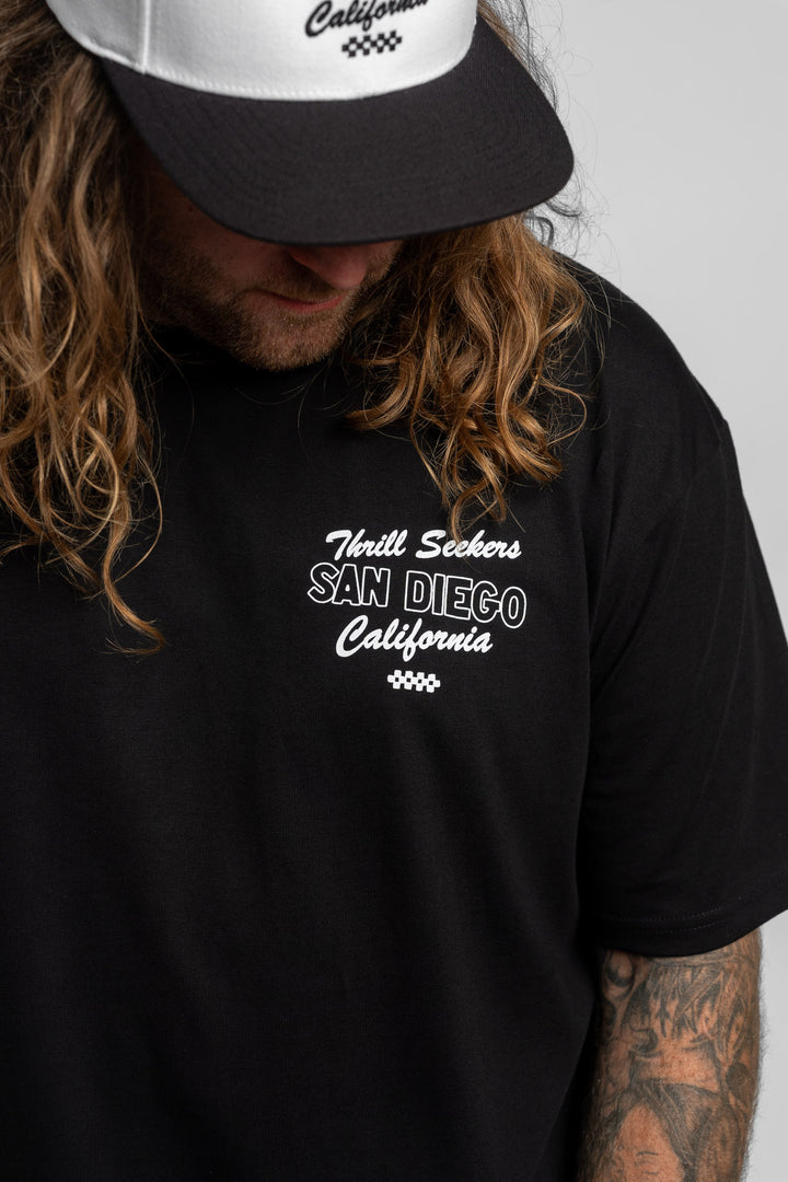 Person wearing black tee with 'Thrill Seekers' shop logo