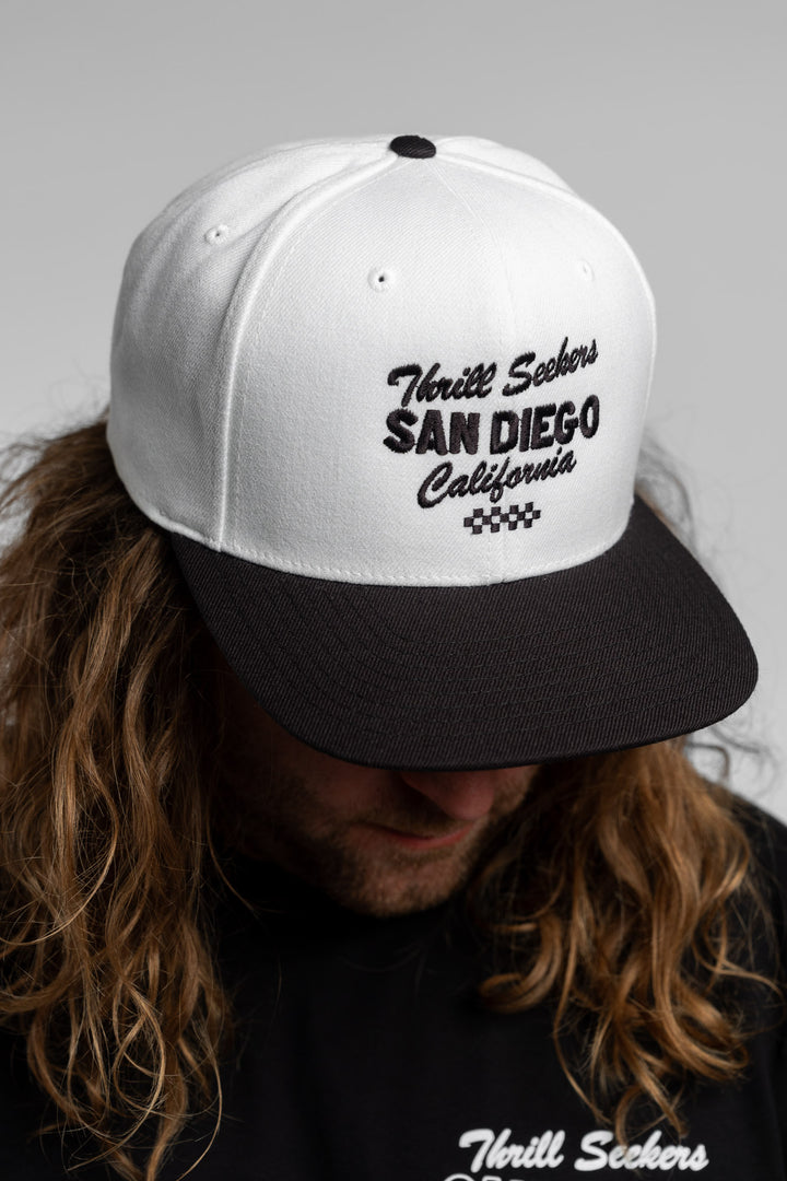 White and black snapback with 'Thrill Seekers' logo in black